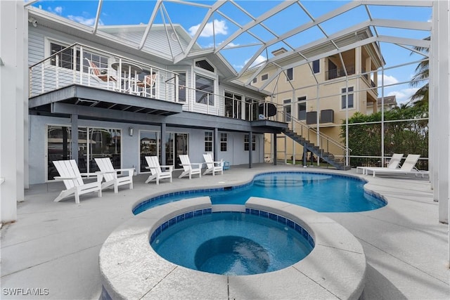 view of swimming pool featuring glass enclosure, a patio area, and an in ground hot tub