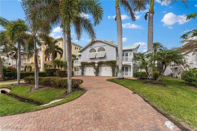 view of front facade with a balcony, a front lawn, and a garage