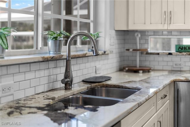 kitchen with white cabinetry, light stone countertops, sink, and tasteful backsplash