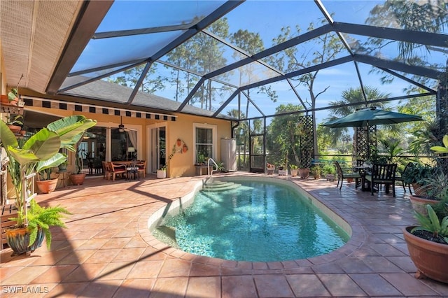 view of swimming pool featuring a patio area, glass enclosure, and ceiling fan