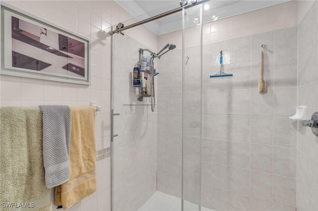 bathroom featuring a shower with shower door and ornamental molding