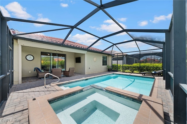 view of pool featuring glass enclosure, an outdoor hangout area, ceiling fan, an in ground hot tub, and a patio