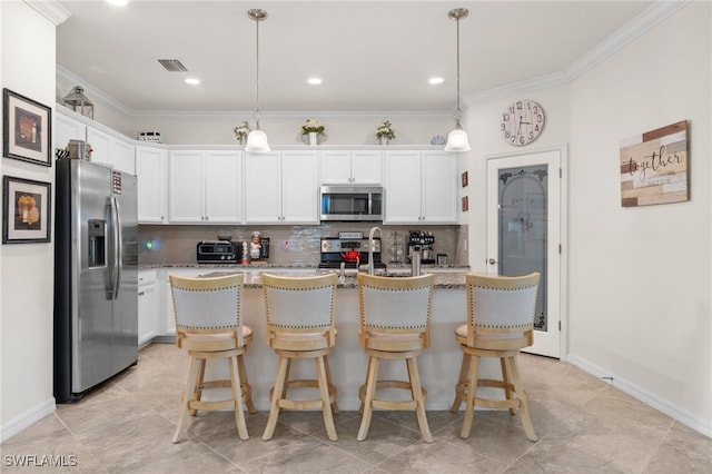 kitchen with decorative light fixtures, stainless steel appliances, white cabinetry, and an island with sink