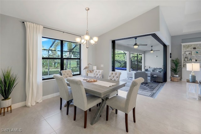 dining space with ceiling fan with notable chandelier, light tile patterned flooring, plenty of natural light, and vaulted ceiling