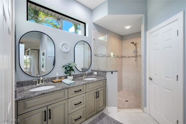 bathroom featuring tile patterned flooring, a tile shower, and vanity