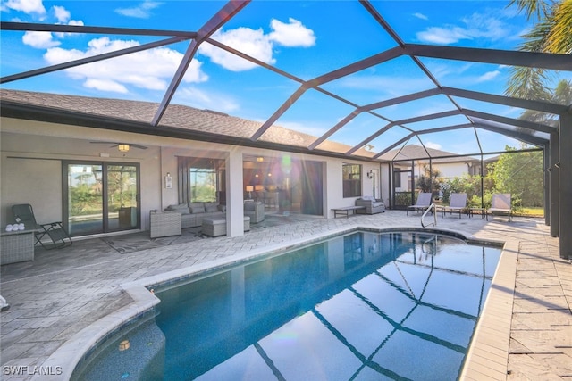 view of swimming pool featuring glass enclosure, ceiling fan, a patio area, and an outdoor living space