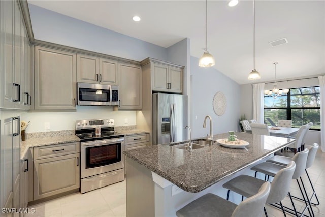 kitchen with stone counters, sink, an island with sink, appliances with stainless steel finishes, and decorative light fixtures