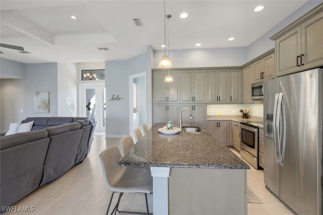 kitchen with pendant lighting, sink, a breakfast bar area, an island with sink, and stainless steel appliances