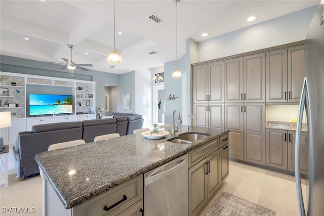 kitchen with a center island with sink, dark stone countertops, sink, and stainless steel appliances