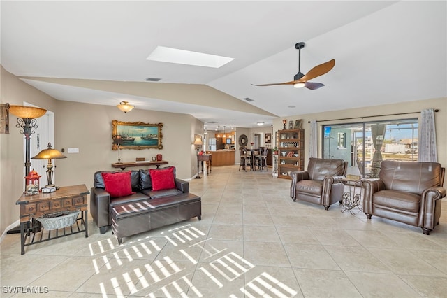 living room featuring ceiling fan, vaulted ceiling with skylight, and light tile patterned flooring