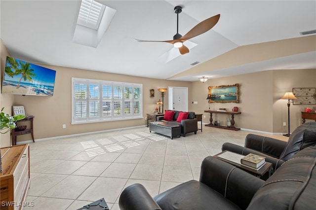 living room featuring light tile patterned floors, ceiling fan, and vaulted ceiling with skylight