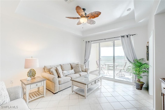 tiled living room featuring a tray ceiling and ceiling fan