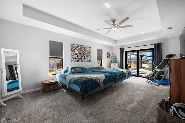 bedroom with ceiling fan, carpet flooring, a tray ceiling, and access to exterior