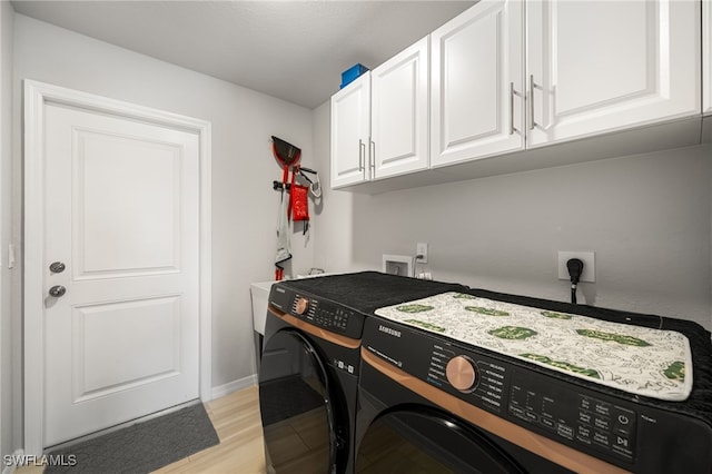 laundry area featuring cabinets, washing machine and clothes dryer, and light hardwood / wood-style floors