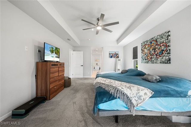 bedroom featuring a raised ceiling, carpet flooring, and ceiling fan