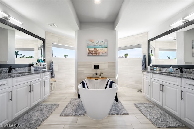 bathroom with vanity, plenty of natural light, and tile walls