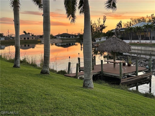 view of dock with a water view and a yard