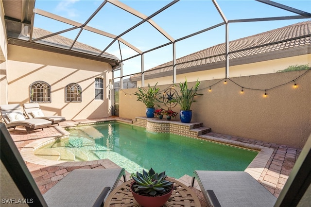 view of pool with glass enclosure and a patio area