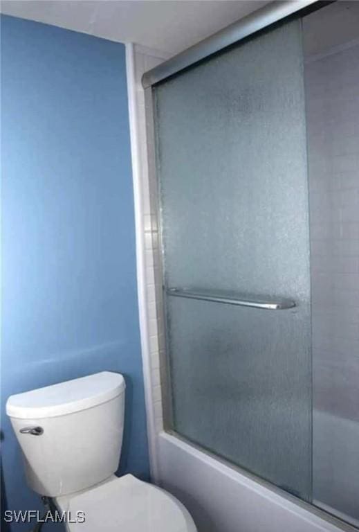 bathroom with toilet and bath / shower combo with glass door