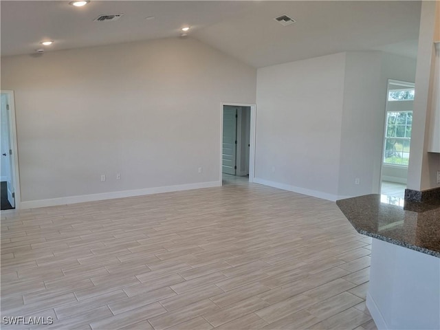 unfurnished room featuring lofted ceiling and light hardwood / wood-style flooring