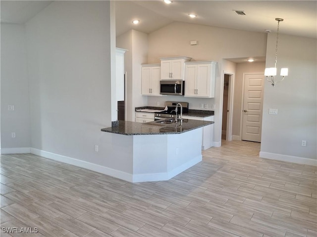 kitchen featuring sink, white cabinetry, stainless steel appliances, decorative light fixtures, and dark stone counters