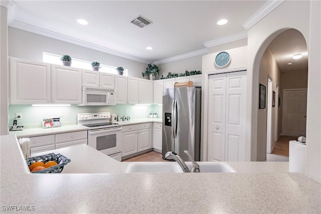 kitchen featuring white cabinetry, sink, white appliances, light tile patterned floors, and ornamental molding