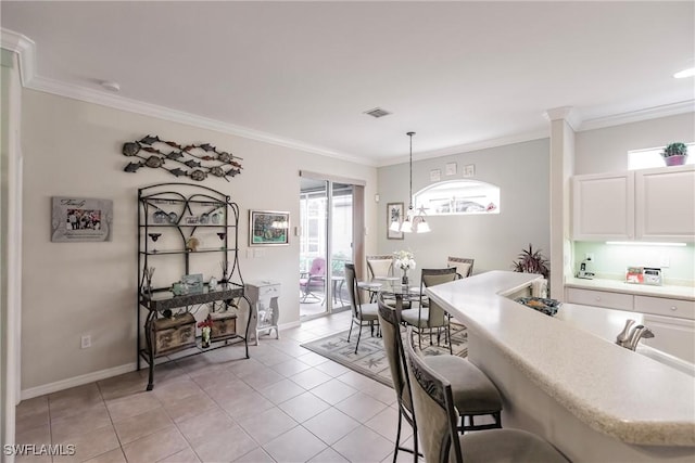 kitchen featuring light tile patterned floors, decorative light fixtures, white cabinetry, and crown molding