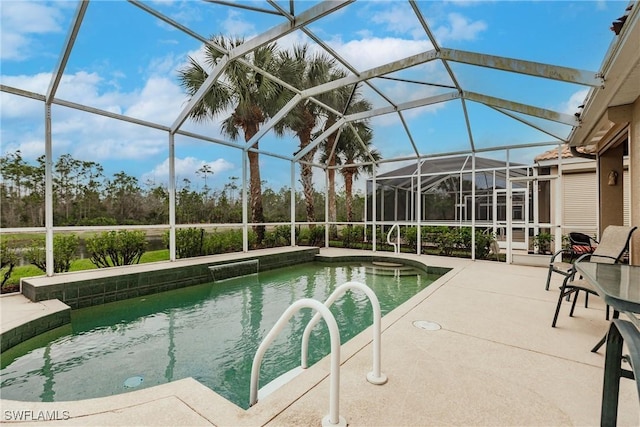 view of pool with glass enclosure, a patio area, and a hot tub