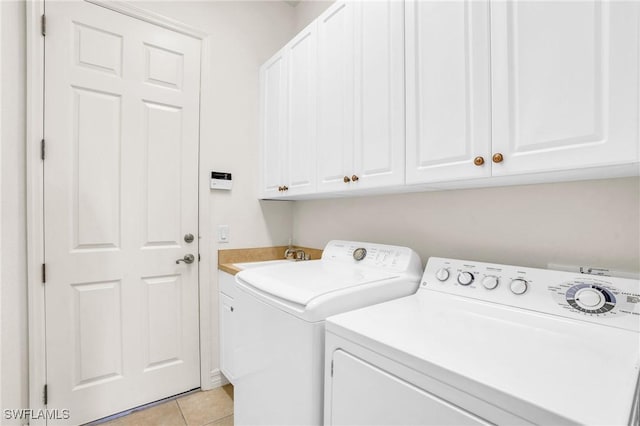 laundry room with washing machine and clothes dryer, sink, light tile patterned floors, and cabinets