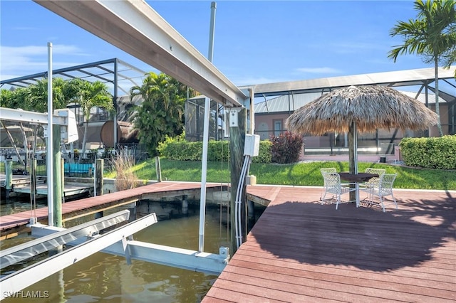 view of dock featuring a lanai, a yard, and a water view