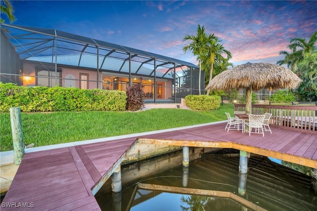 view of dock with glass enclosure and a yard