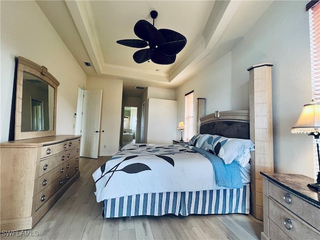 bedroom with light hardwood / wood-style flooring, a raised ceiling, ceiling fan, and crown molding