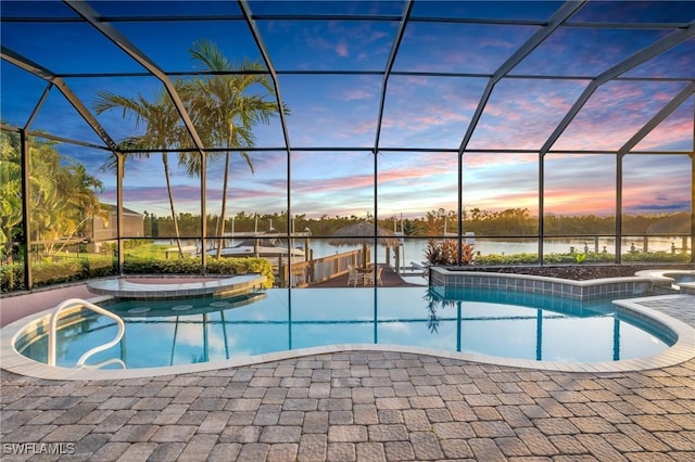 pool at dusk with glass enclosure, a patio, and a hot tub