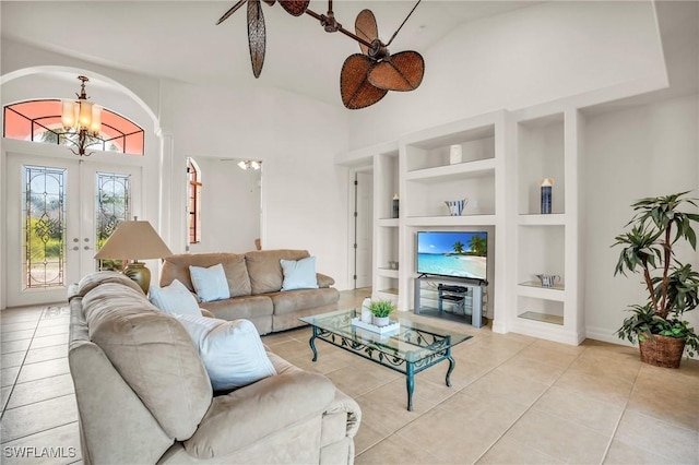 living room featuring built in shelves, ceiling fan with notable chandelier, light tile patterned floors, and french doors