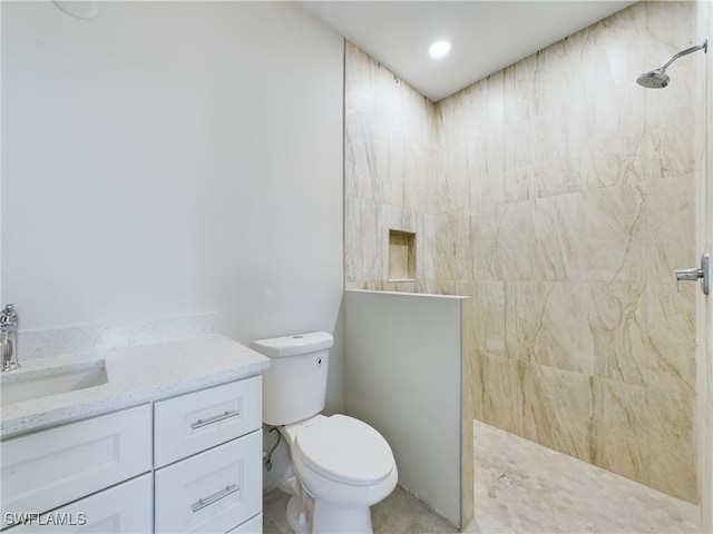 bathroom with tiled shower, vanity, and toilet