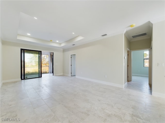 unfurnished room featuring a tray ceiling, a wealth of natural light, and ornamental molding