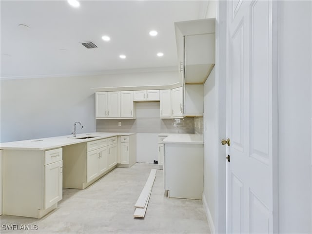 kitchen featuring tasteful backsplash, white cabinetry, ornamental molding, and sink