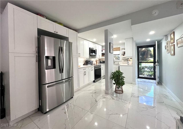 kitchen featuring decorative backsplash, white cabinetry, and appliances with stainless steel finishes