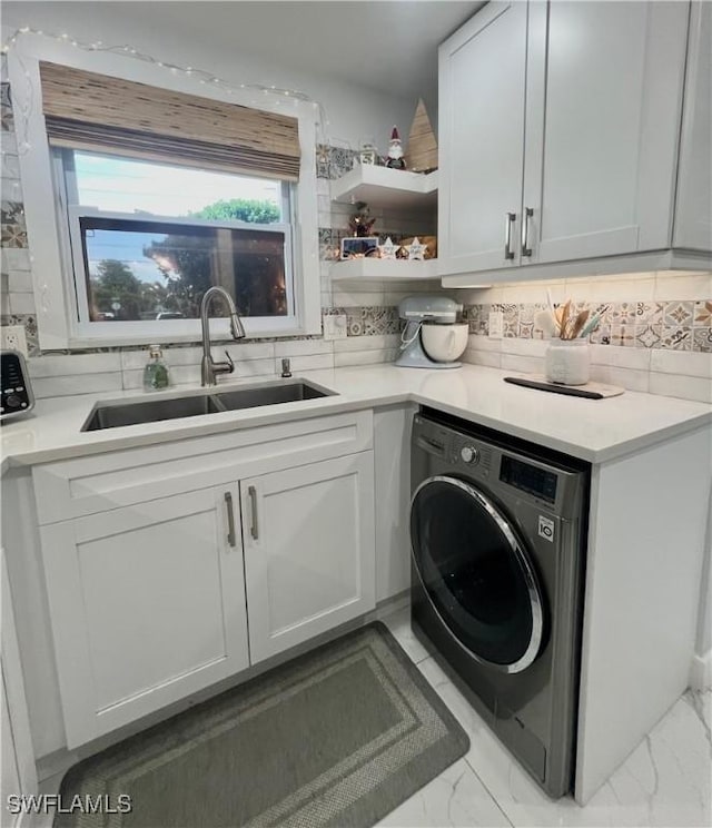 clothes washing area with sink, washer / clothes dryer, and cabinets