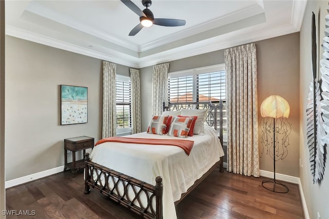 bedroom featuring dark hardwood / wood-style flooring, a tray ceiling, and ceiling fan