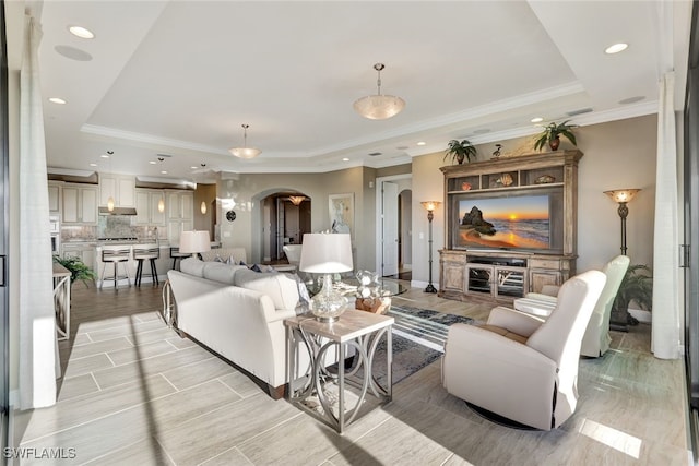 living room featuring a raised ceiling and ornamental molding