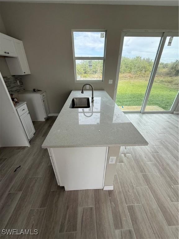 kitchen with light stone countertops, white cabinetry, and sink