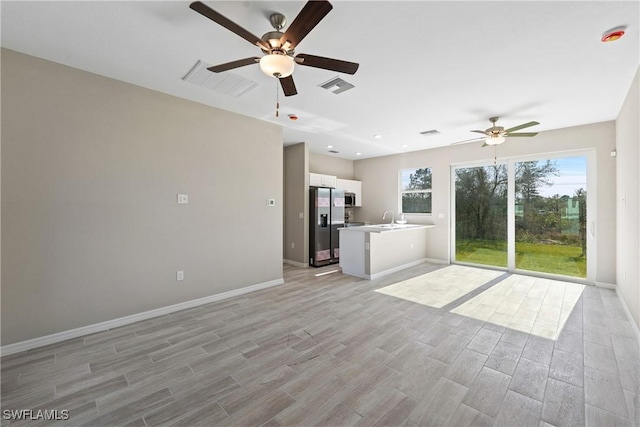 unfurnished living room with sink, light hardwood / wood-style flooring, and ceiling fan