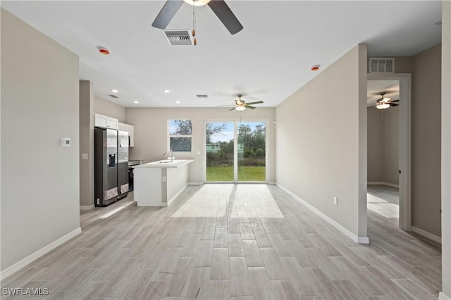 unfurnished living room featuring ceiling fan, sink, and light hardwood / wood-style floors