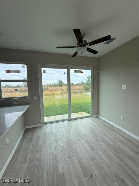 unfurnished room featuring ceiling fan, light hardwood / wood-style floors, and plenty of natural light