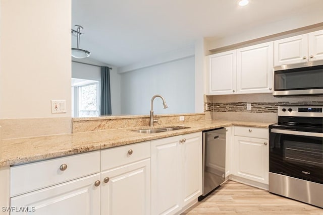 kitchen with white cabinetry, sink, light stone counters, decorative backsplash, and appliances with stainless steel finishes