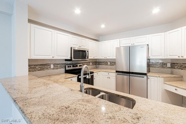 kitchen with white cabinets, appliances with stainless steel finishes, and light stone counters