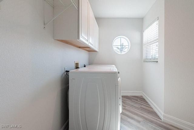 laundry room with washer / clothes dryer, light hardwood / wood-style flooring, and cabinets