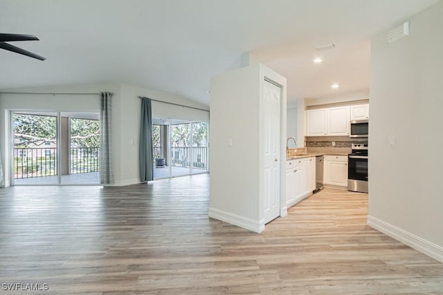 kitchen featuring white cabinets, sink, light wood-type flooring, appliances with stainless steel finishes, and tasteful backsplash