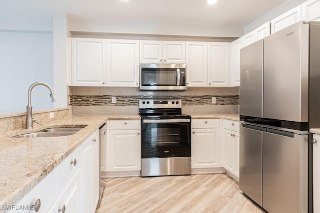 kitchen with light stone countertops, sink, decorative backsplash, white cabinets, and appliances with stainless steel finishes